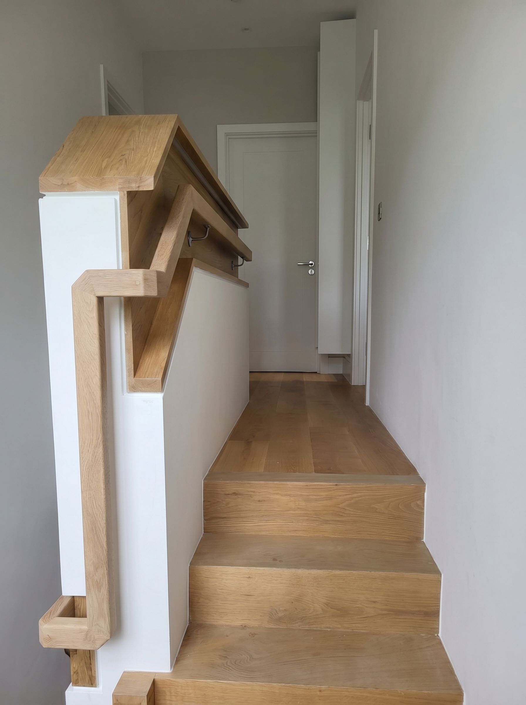 Detail of a bespoke oak staircase with sculpted handrail and white painted balustrade leading to the upper floor hallway, Islington London