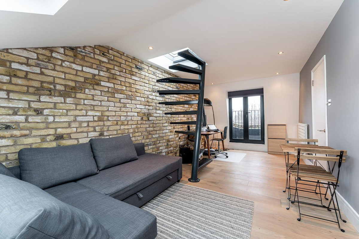 Loft conversion living area with exposed brick feature wall, spiral staircase and Juliet balcony, Hackney London