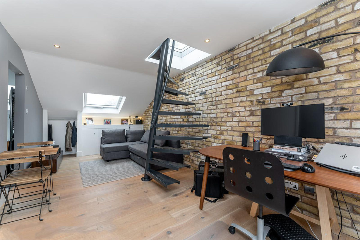 Loft conversion with black spiral staircase, exposed London stock brick wall and skylights, Hackney London