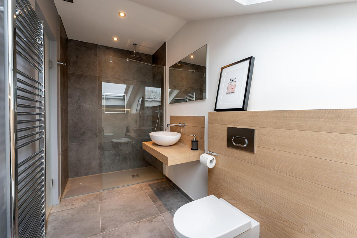Modern loft ensuite bathroom with walk-in shower, oak wall panelling and countertop basin, Hackney London