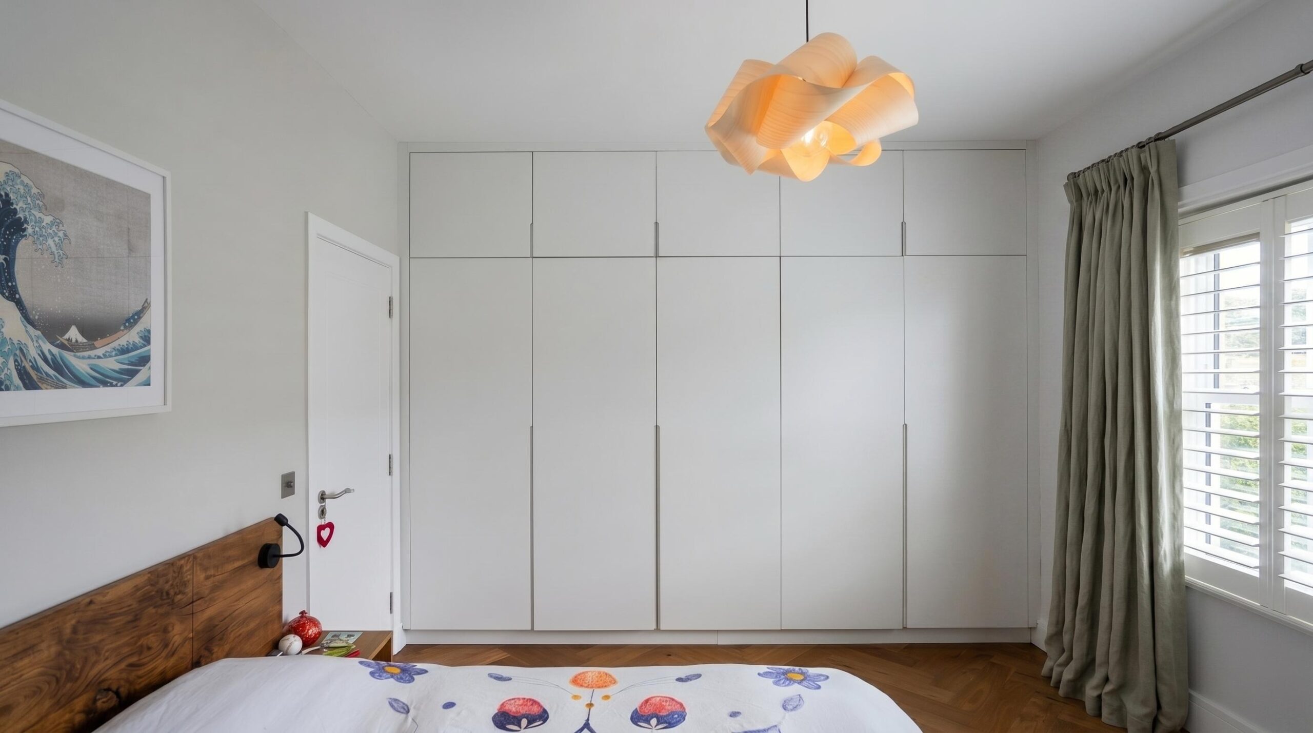 Master bedroom with bespoke handleless wardrobes, walnut headboard, herringbone parquet flooring and sculptural pendant light, Islington London