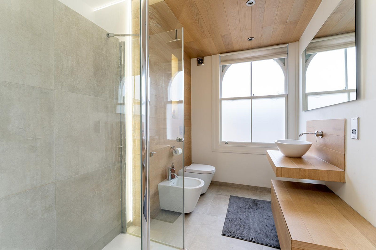 Bathroom renovation in a period property with walk-in shower, oak vanity unit and original arched sash window, Hackney London
